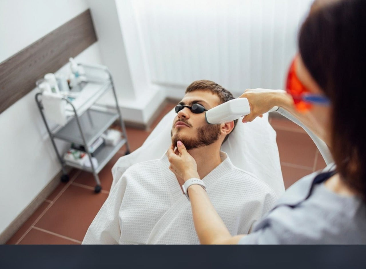 Man receiving professional laser hair removal treatment on face with modern machine in beauty clinic while wearing protective eyewear